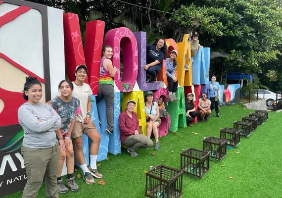 Students lined up in front of sculptural sign reading "Volcan Masaya"