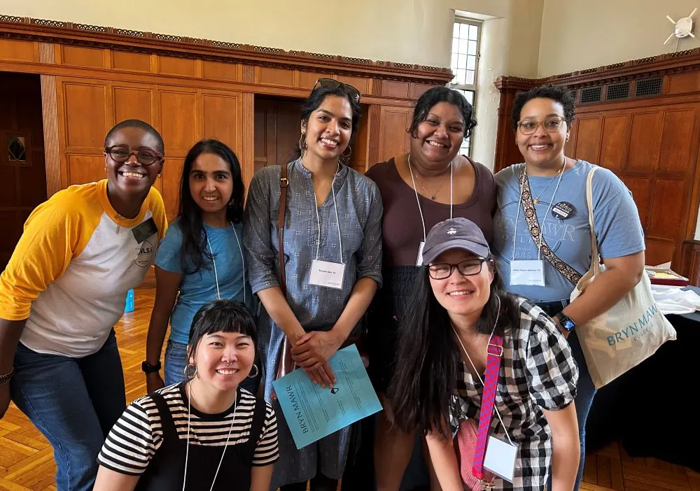 A group of alums stand together and smile at the camera.