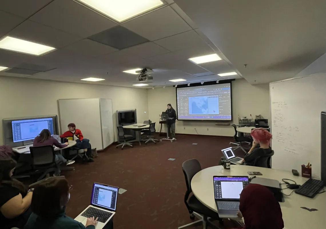 a presenter in the DMCL with people on laptops and a display board showing a map