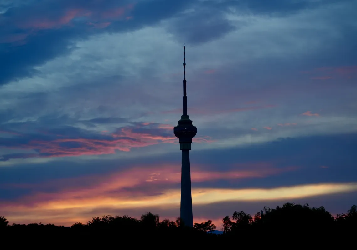 a CCTV tower in Beijing contrasting with a sunset