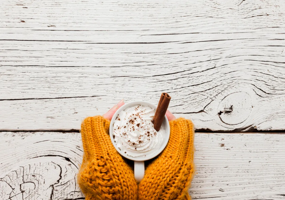 Hands in yellow sweater holding coffee