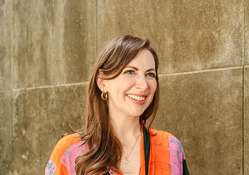 Emily Alesandrini in orange and pink shirt in front of concrete wall