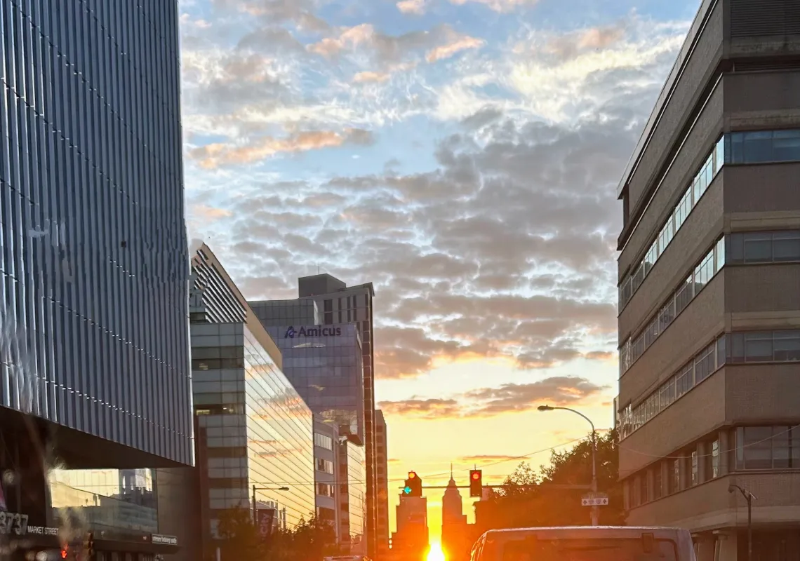 View of sun rising through buildings.