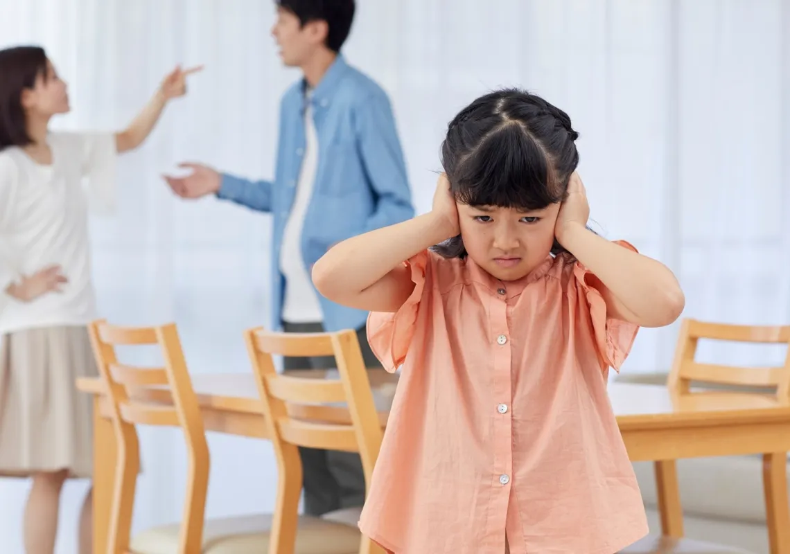 Image of parents fighting with child holding her ears