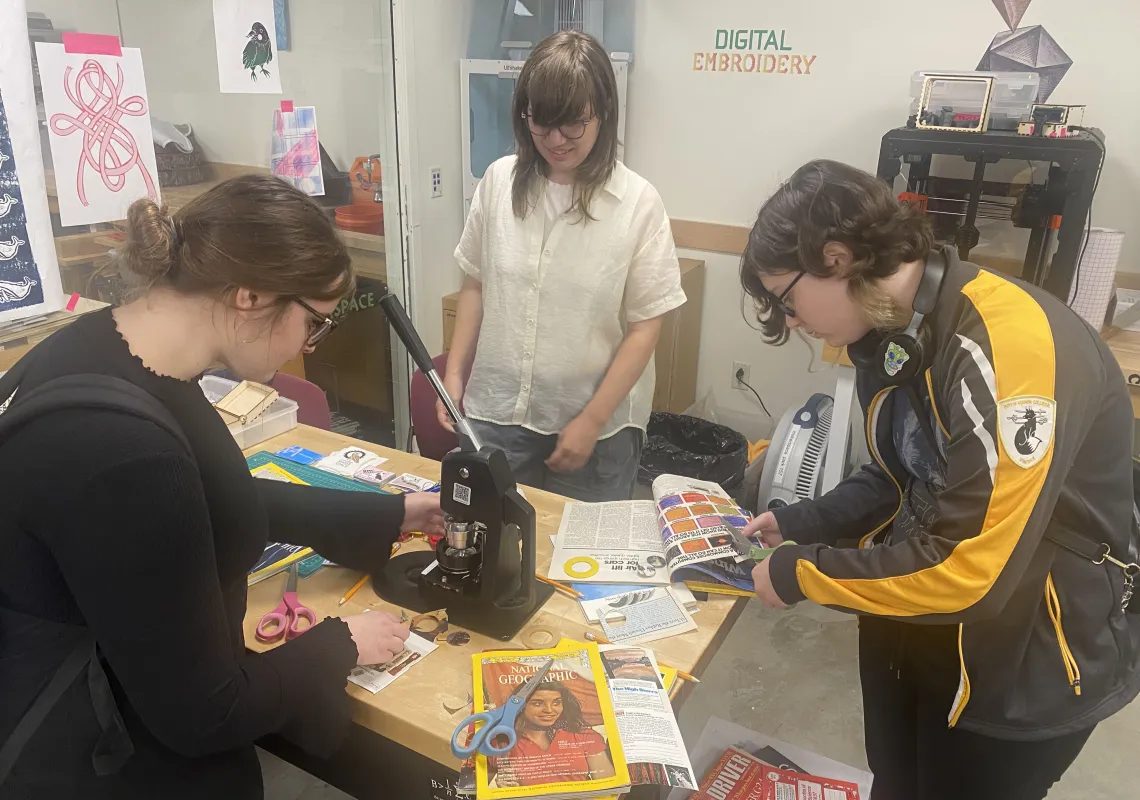 Annika Bergstrom, EAST Educational Technology Assistant, works with students using the Makerspace's button maker