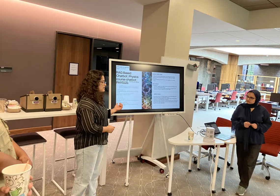 The 2026 Digital Technology Interns, Pragya Silwal '27 and Yumna Fatima Dar '29, present on their AI tools using a poster board during a showcase at Haverford College