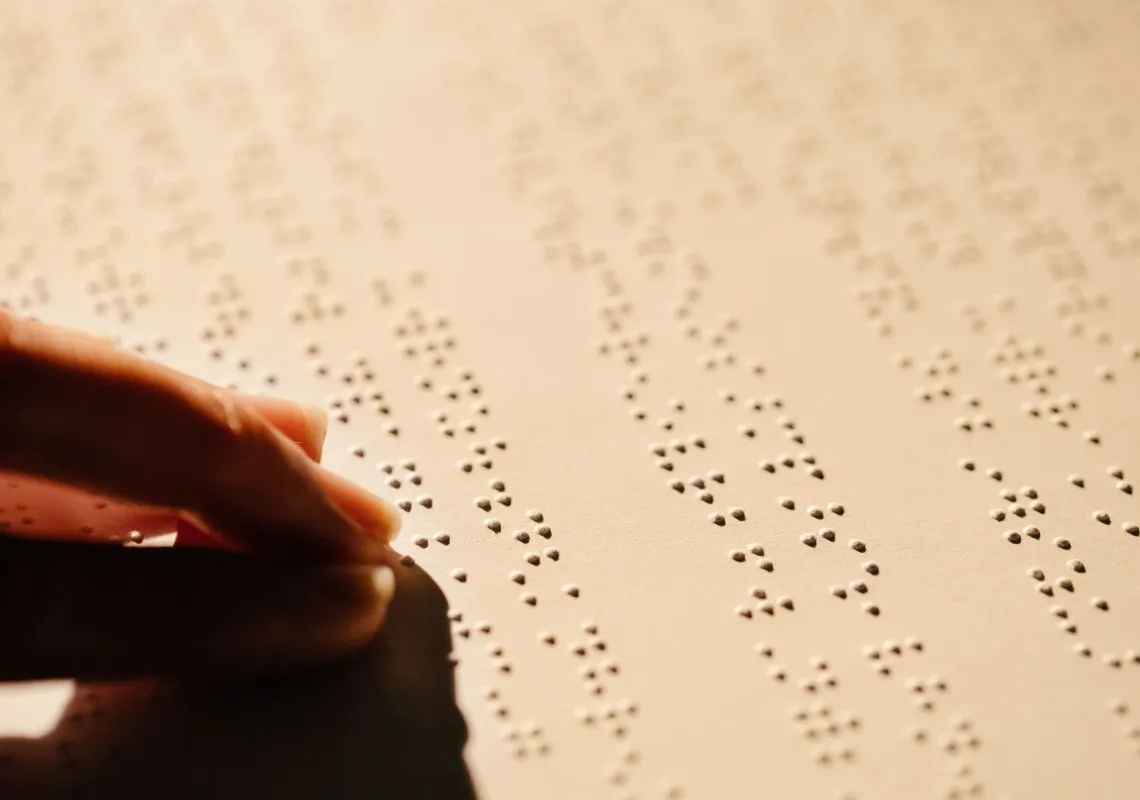 fingers on a page reading braille by touch