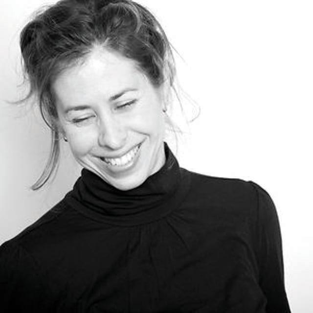 Black and white portrait of Amy Neswald, smiling with closed eyes.