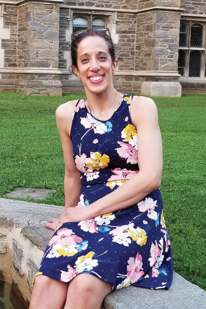 Marissa Patterson sitting on a short stone wall in a floral dress