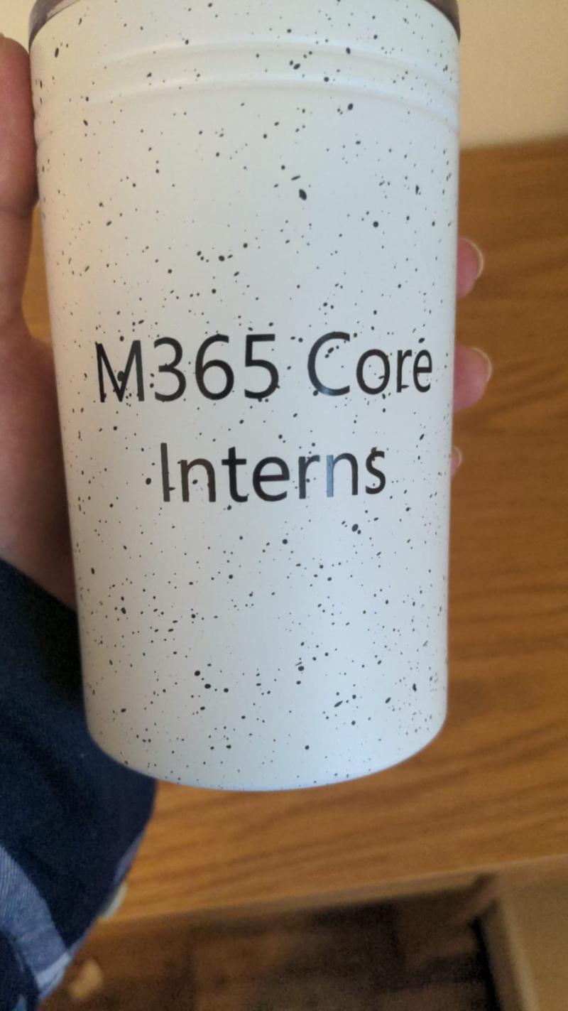White cup with text that reads "M365 core interns"