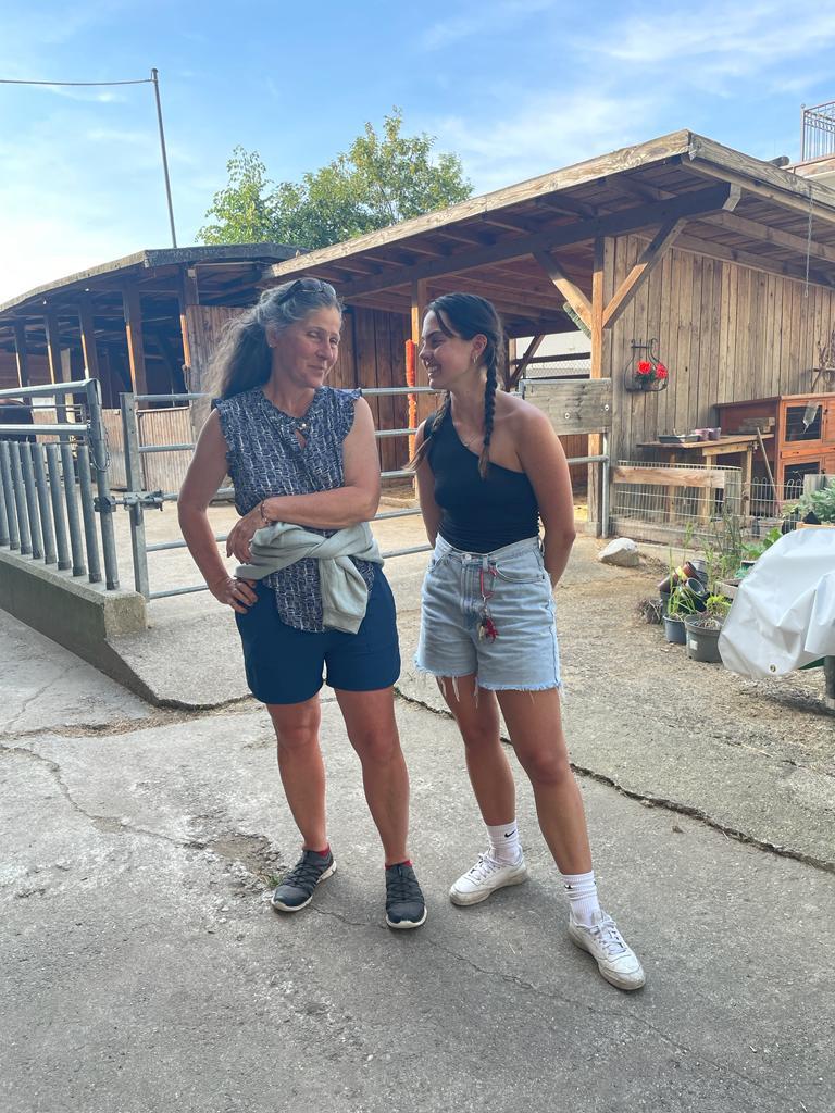 Two women outside of a barn. 