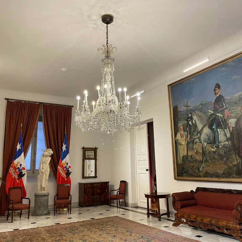 Room with chandelier and large painting. 