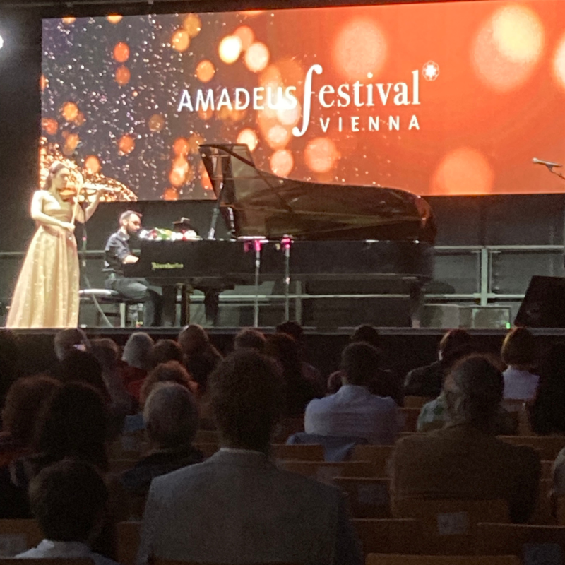 Audience watching a stage with a violinist and pianist performing