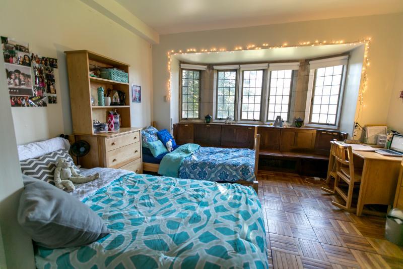 Dorm room with two beds and a window seat