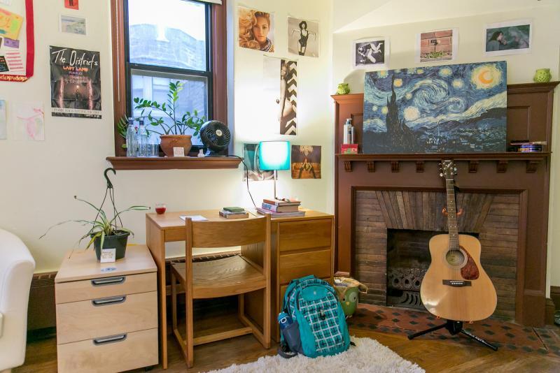 Dorm room with fireplace, desk, and guitar