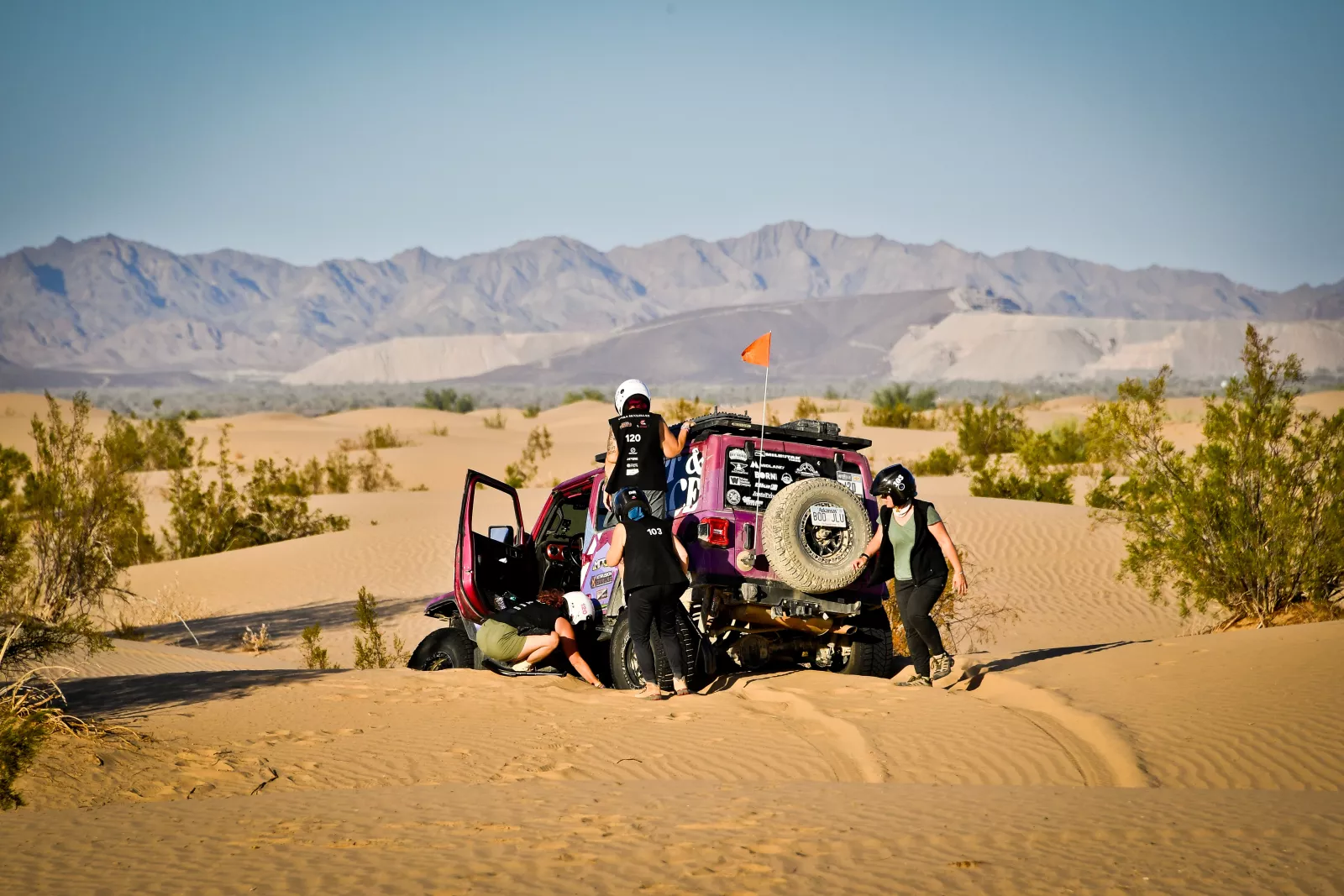 Drivers dig a car out of the sand at the Rebelle Rally