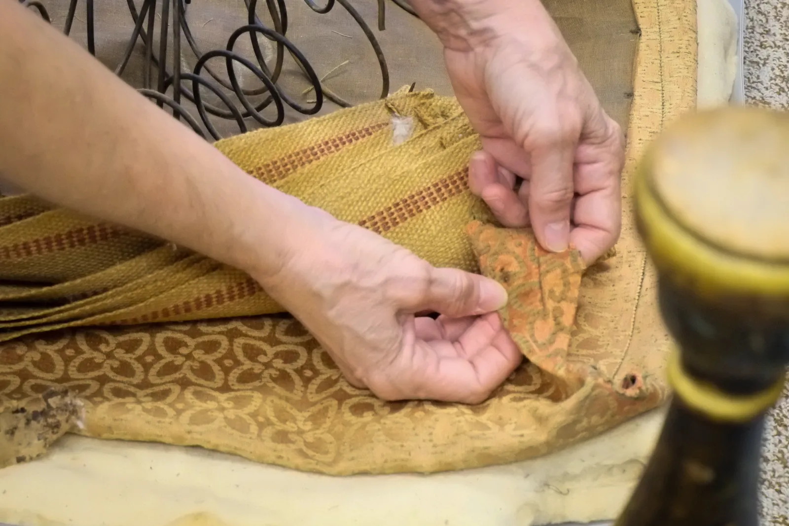 Kathy Gillis of Winterthur inspects the fabric inside a seam on the antique chair.