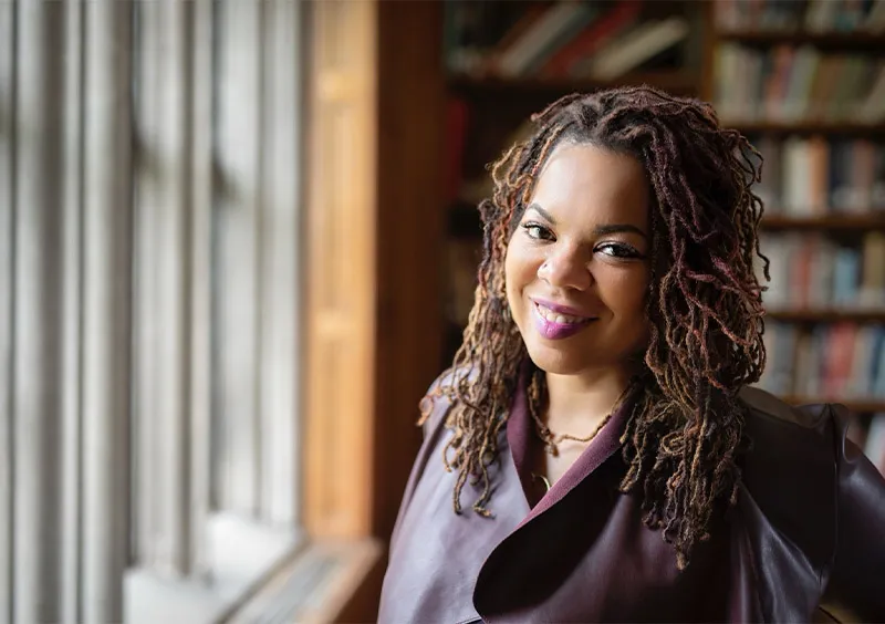 Dee Matthews portrait in front of bookshelves
