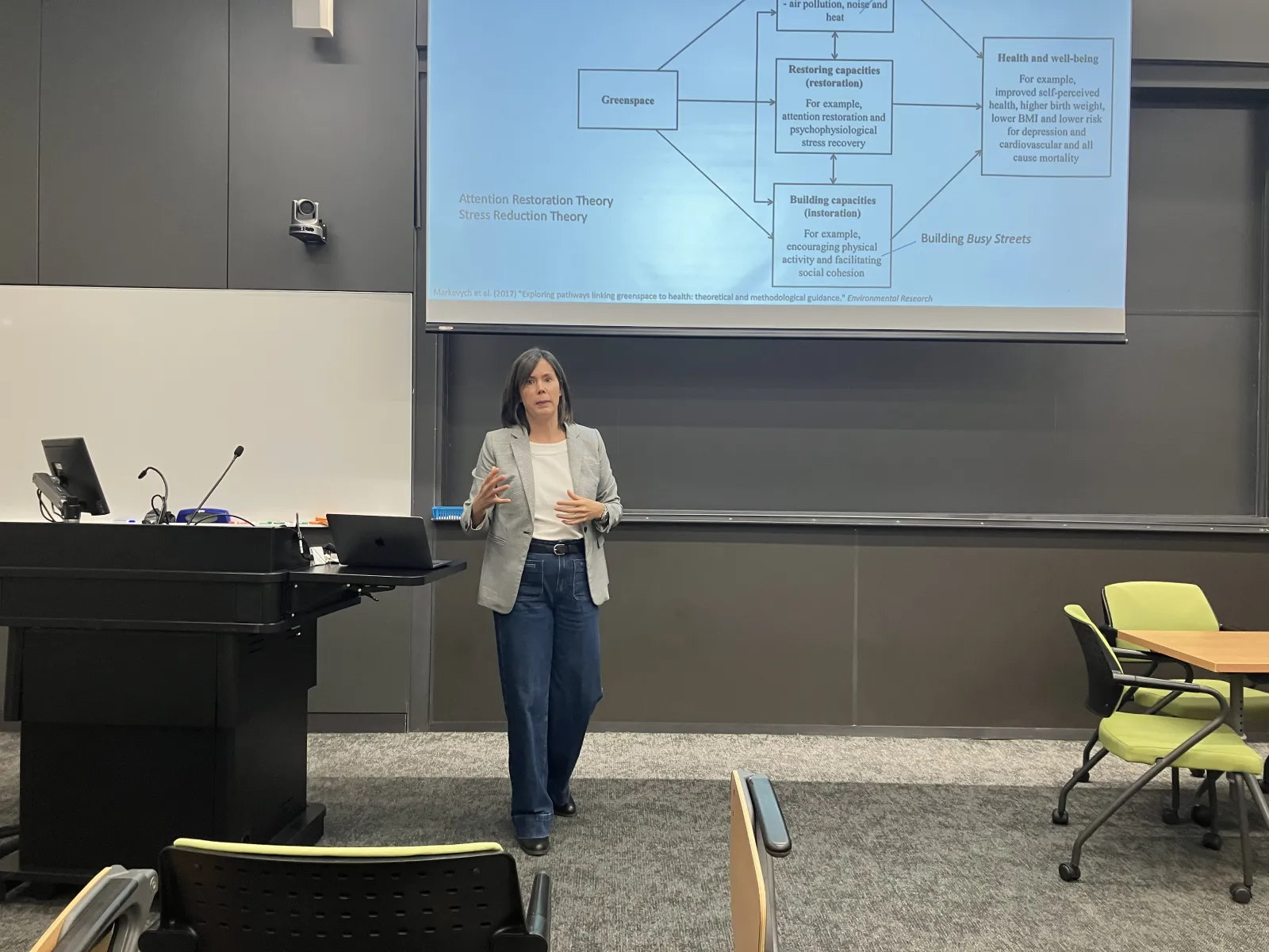 A woman presenting in the front of a classroom. 