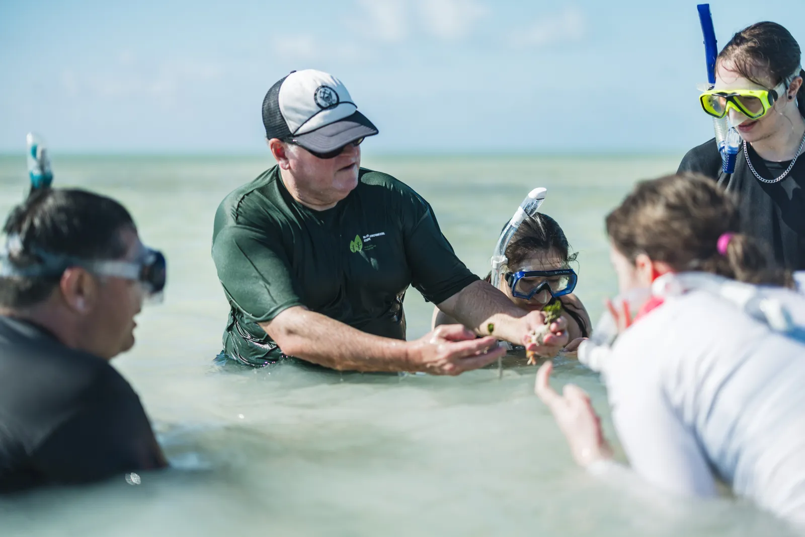 geology professor talks with students in shallow water