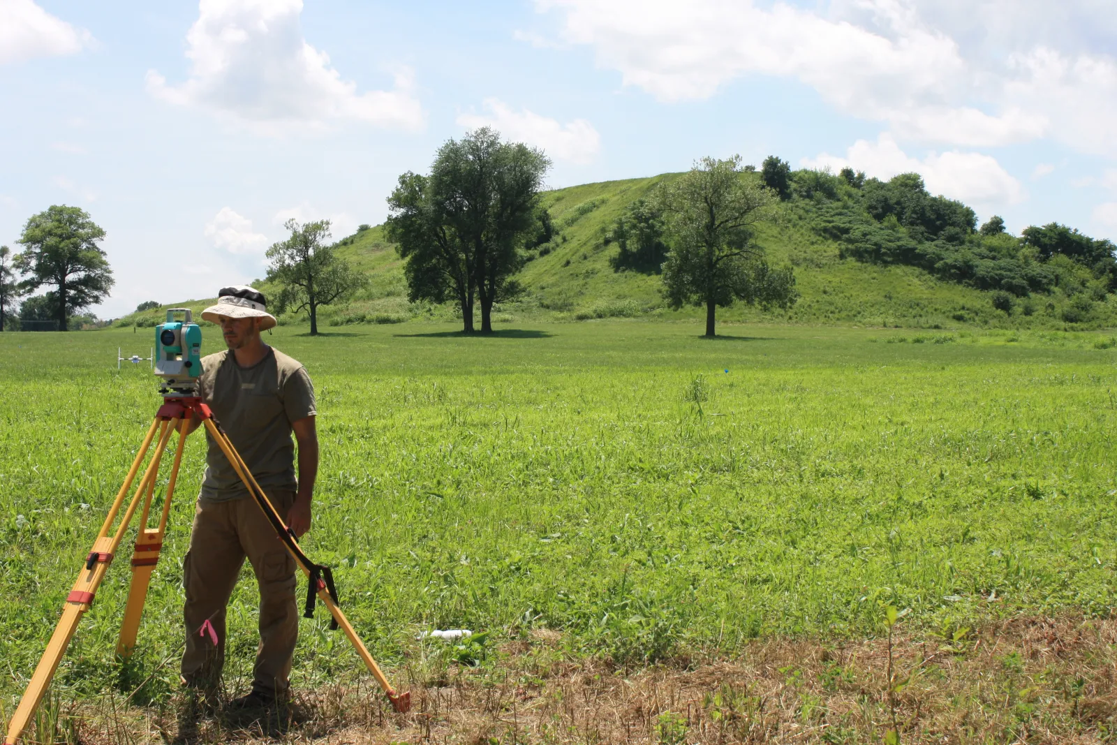 Man using survey tool in field.