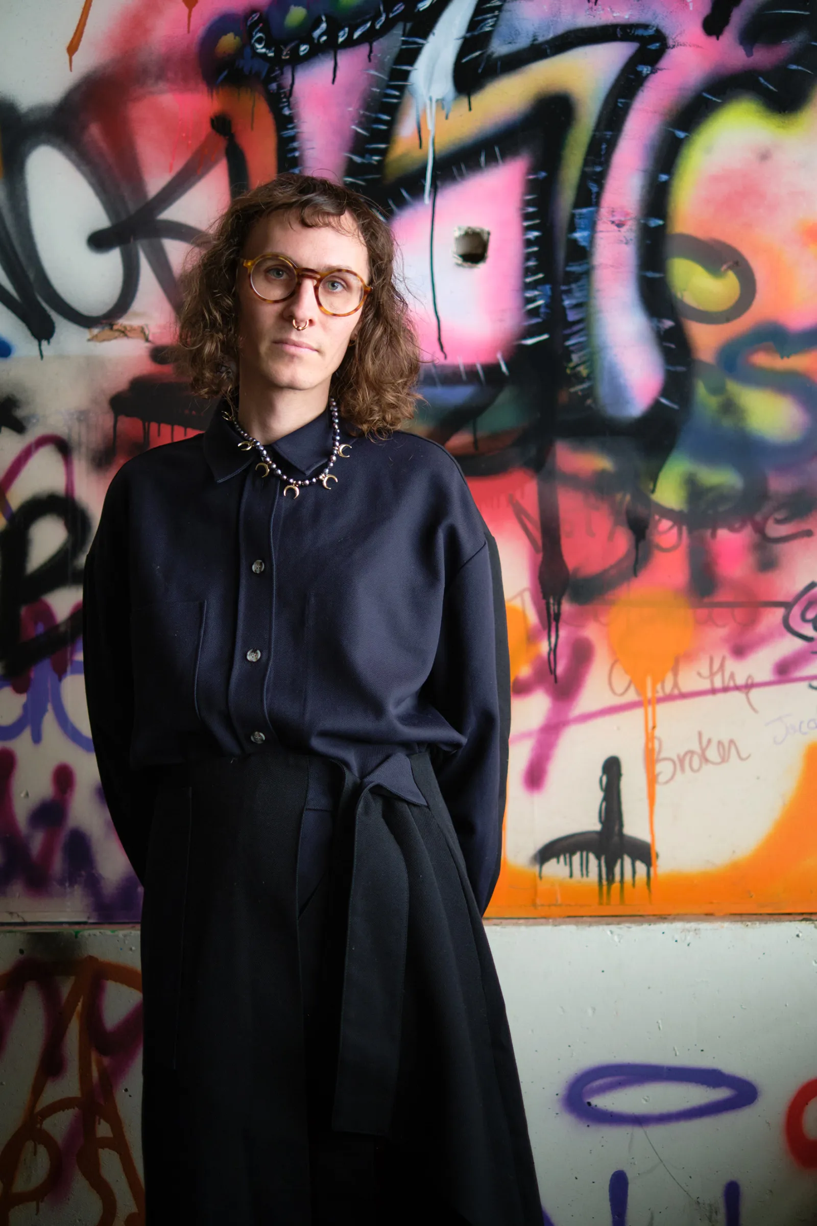 C.C. McKee portrait in front of wall of graffiti