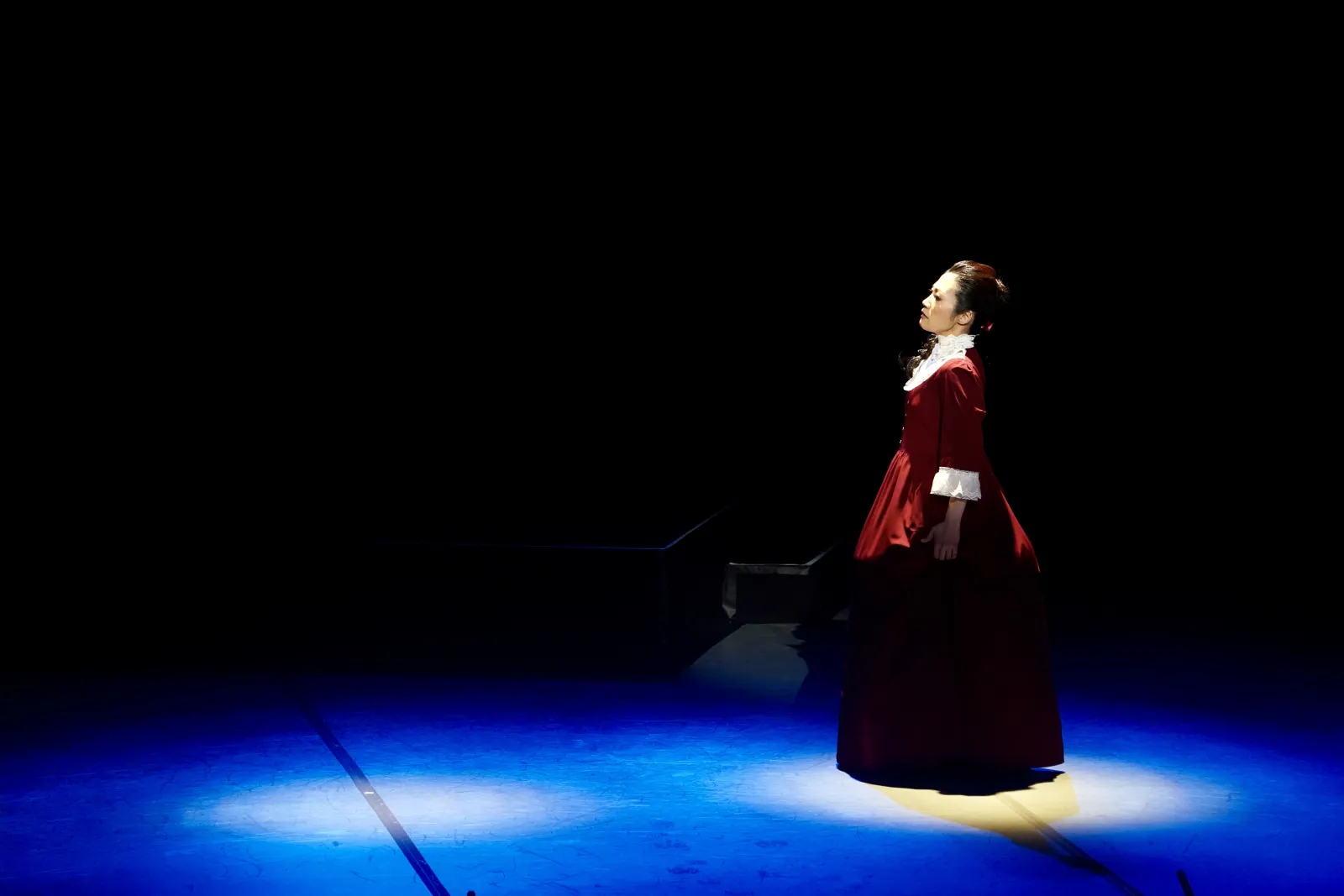 The character of Umeko Tsuda stands on a dark stage
