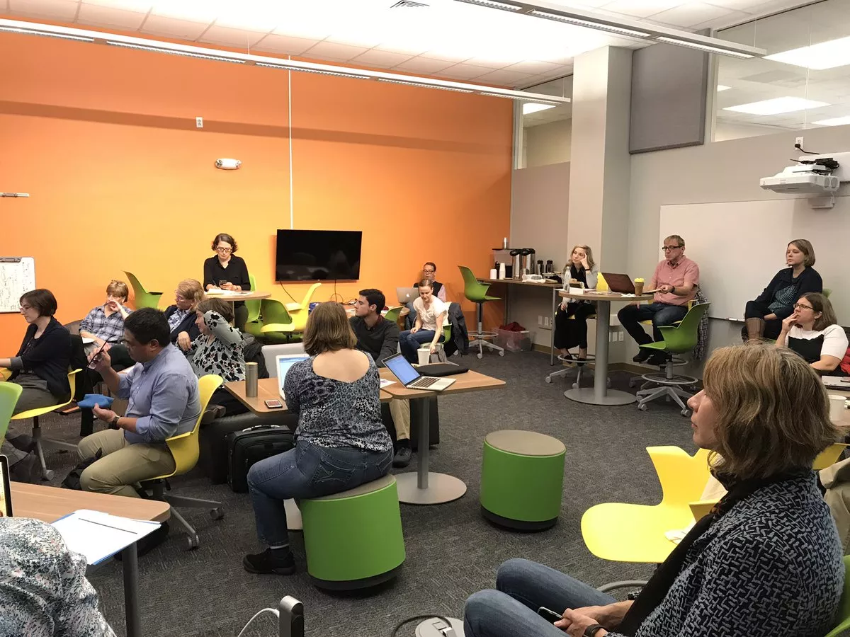 A group of people in a colorful room, working.
