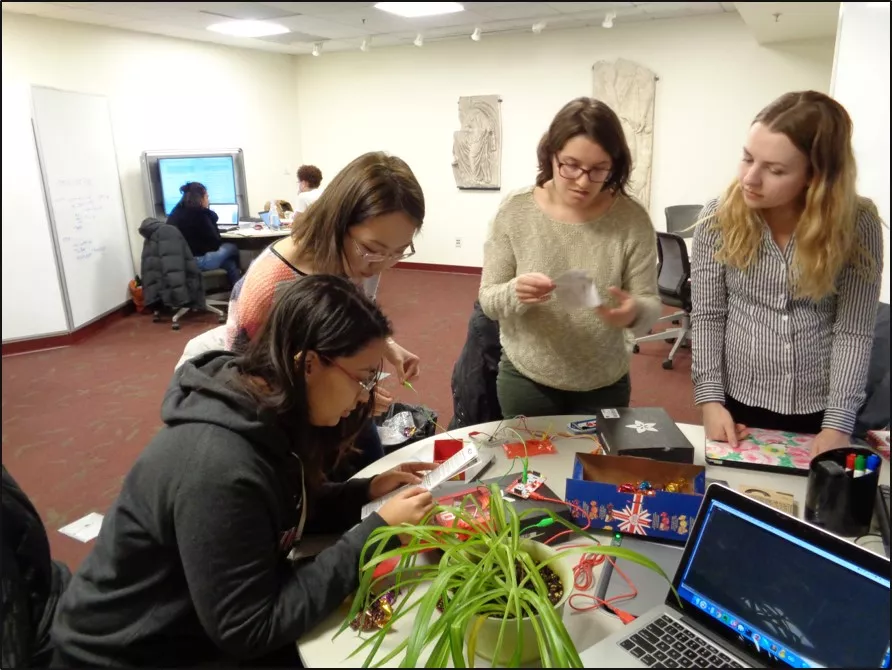 Four students with wires and a plant.
