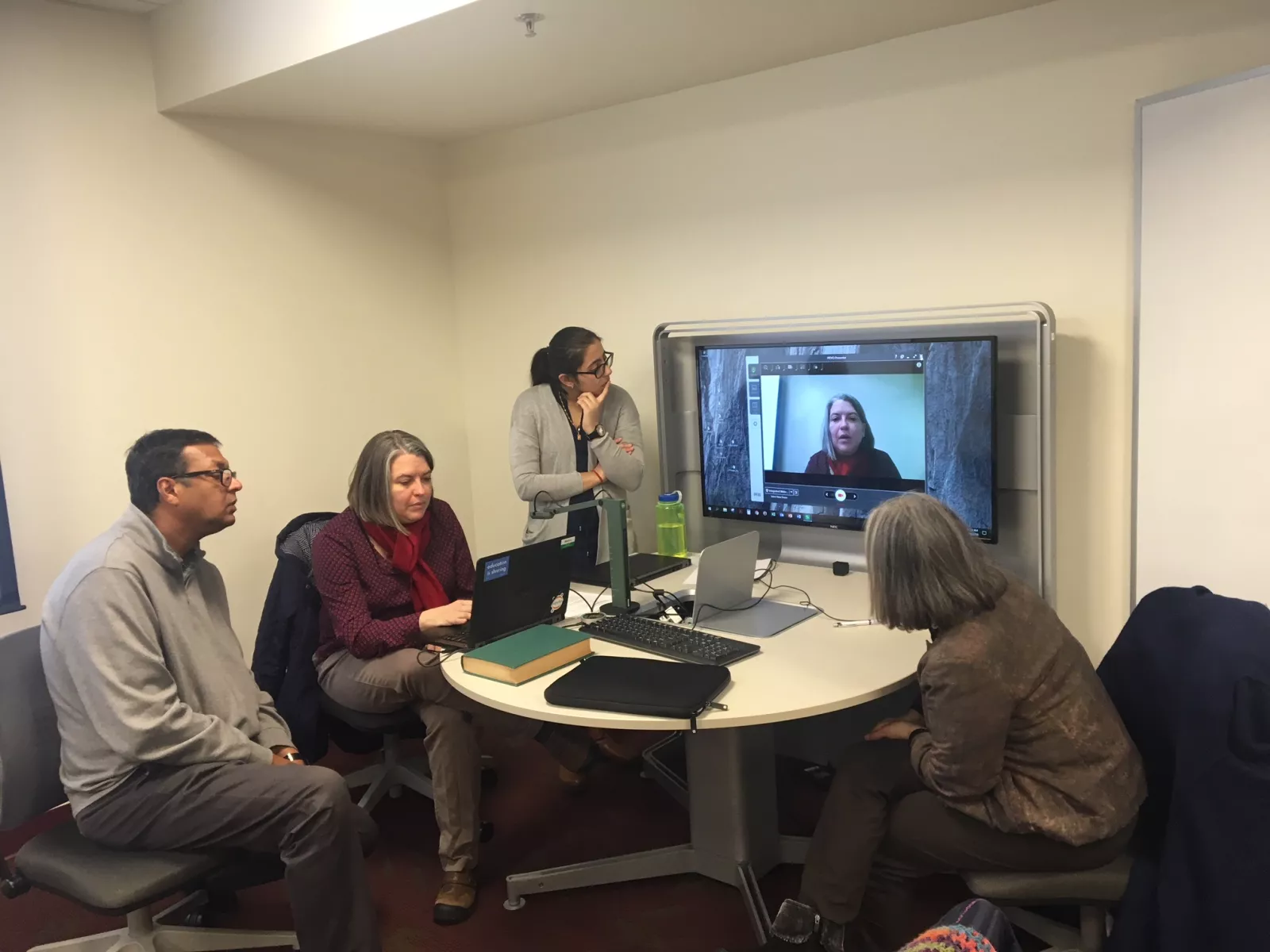 People around a desk with projection equipment.