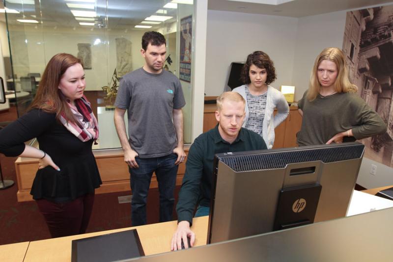 Graduate students huddle in front of computer