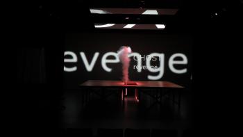 A billow of smoke is coming out of a wood table on a dark stage, and the words "revenge" and "ghost" are projected in white in the background.